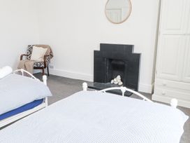 A bedroom with two single beds a black fireplace a white wardrobe and a chair with a cushion and blanket at Dolawen Bach Conwy