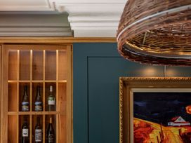 A wine cellar with wine bottles in a wooden cabinet and a framed painting at Leathes Head Country House Borrowdale near Keswick