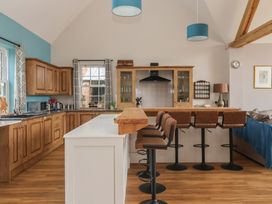 A kitchen with wooden cabinetry and bar stools at Crossett Grange in Driffield