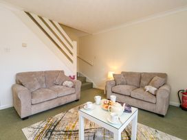 A living room with two beige sofas and a white coffee table with cups and pastries at Dorset Explorers in Bournemouth