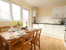 A kitchen with a wooden dining table set for four and white cabinets at Dorset Explorers in Bournemouth