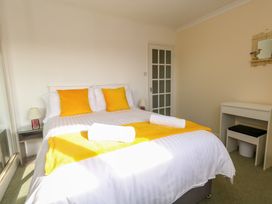A bedroom with a bed with yellow cushions and runners two rolled towels bedside tables with lamps a dressing table and a mirror at Dorset Explorers in Bournemouth