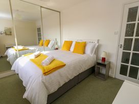 A bedroom with a double bed with yellow pillows and blanket beside a nightstand with a lamp and glass at Dorset Explorers in Bournemouth