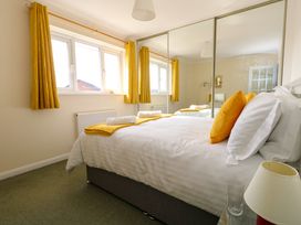 A bedroom with a bed white linens yellow pillows and curtains and mirrored wardrobe doors at Dorset Explorers in Bournemouth