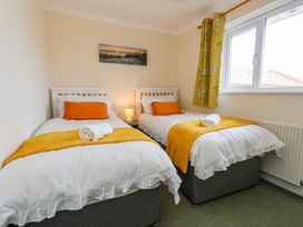 A bedroom with two single beds with white bedding yellow throws and orange pillows at Dorset Explorers in Bournemouth