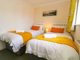 A bedroom with two single beds with white bedding and orange cushions at Dorset Explorers in Bournemouth