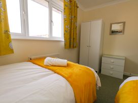 A bedroom with two beds yellow blankets and white wardrobes and drawers at Dorset Explorers in Bournemouth