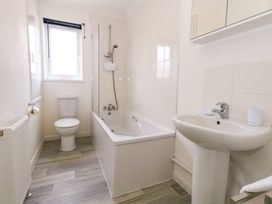 A bathroom with a toilet a bathtub with shower a sink and a window at Dorset Explorers in Bournemouth