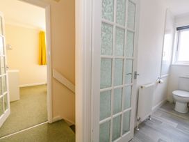 A hallway showing a bathroom with a toilet and radiator and a room with green carpet and yellow curtains at Dorset Explorers in Bournemouth