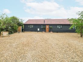 A single-story building with a tiled roof two potted plants by the door and gravel driveway at The Ivy in Happisburgh East Anglia