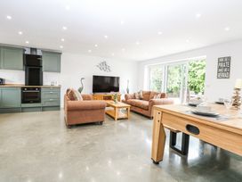 An open plan living room with brown sofas a wooden coffee table green kitchen cabinets and a wooden dining table at The Ivy in Happisburgh East Anglia