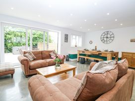 A living room with brown sofas a wooden coffee table and a dining area with wooden table and bench at The Ivy in Happisburgh East Anglia