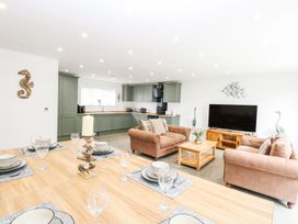 An open plan living room and kitchen with dining table set with plates and glasses at The Ivy in Happisburgh East Anglia