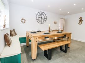 A dining area with a wooden table and bench and built in seating with cushions at The Ivy in Happisburgh East Anglia