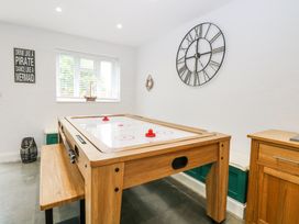 A game room with an air hockey table a large wall clock a window and wooden cabinets at The Ivy in Happisburgh East Anglia