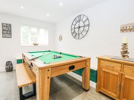 A game room with a pool table bench a wooden cabinet and a clock on the wall at The Ivy in Happisburgh East Anglia