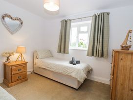 A bedroom with a single bed bedside table lamp and wooden chest of drawers at The Ivy in Happisburgh East Anglia