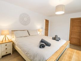 A bedroom with a large bed and rolled towels on it two bedside tables with lamps and wooden doors at The Ivy in Happisburgh East Anglia