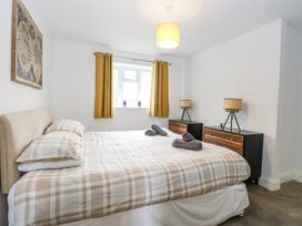 A bedroom with a double bed with plaid bedding two bedside tables with lamps and mustard curtains at The Ivy in Happisburgh East Anglia