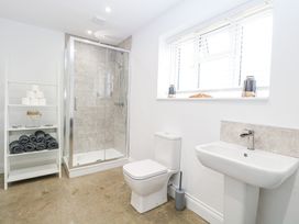 A bathroom with a shower enclosure toilet sink and shelving unit with towels at The Ivy in Happisburgh East Anglia