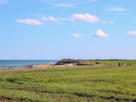 A coastal landscape with green fields and a beach by the sea at The Ivy in Happisburgh East Anglia