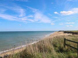 A coastal landscape with a sandy beach grassy cliffs and blue sky at The Ivy in Happisburgh East Anglia