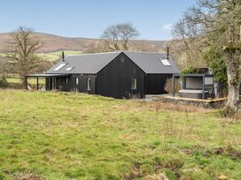 A house with a deck and hot tub on grass at Grove Cottage in Kington