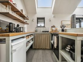 A kitchen with shelves, stove, and sink at Grove Cottage, Kington