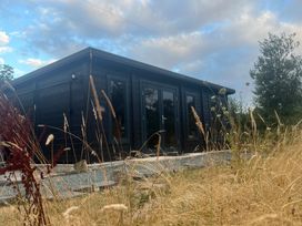 A cabin with windows and door surrounded by grass at Grove Cottage in Gladestry