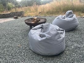 A fire pit with logs and two bean bags at Grove Cottage in Gladestry