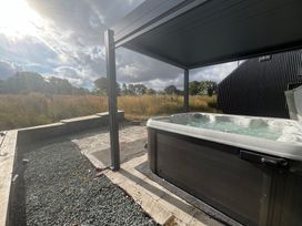 A hot tub on a stone patio in an outdoor area at Grove Cottage in Gladestry
