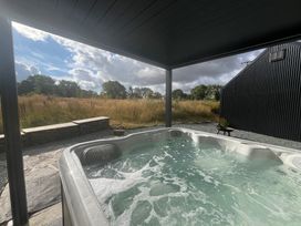A hot tub next to a stone wall at Grove Cottage in Gladestry