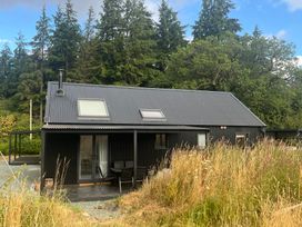 A black building with a deck and chairs at Grove Cottage in Gladestry