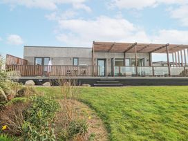 A single story wooden building with a large deck and pergola overlooking a garden at Hepworth in Portreath