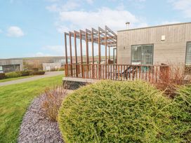 A wooden house with a pergola on the deck and shrubs in the garden at Hepworth in Portreath