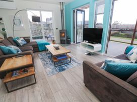 A living room with brown sofas and blue cushions a wooden coffee table wood burner and a television at Hepworth in Portreath