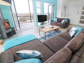 A living room with two brown sofas pillows a wooden coffee table a television a fireplace and an open door to a deck at Hepworth in Portreath