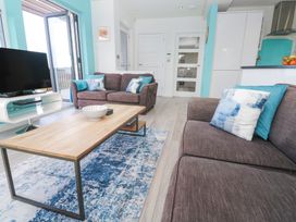 A living room with brown sofas blue and white cushions a wooden coffee table a television on a white stand and a blue patterned rug at Hepworth in Portreath