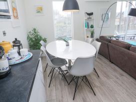 A dining area with a round white table and six grey chairs next to a brown sofa and a black countertop in Hepworth Portreath