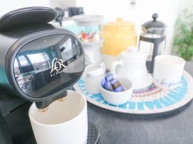 A coffee machine with a white mug and a tray with a teapot cream jar and coffee capsules at Hepworth in Portreath