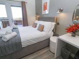 A bedroom with a bed with pillows and folded towels next to a window and a table with flowers at Hepworth in Portreath