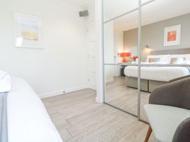 A bedroom with a large bed a bedside table with a lamp and flowers a chair and a mirrored wardrobe at Hepworth in Portreath