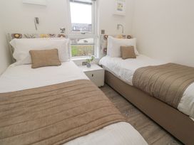 A bedroom with two single beds a nightstand with a flower vase and a window at Hepworth in Portreath