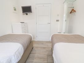 A bedroom with two single beds a chest of drawers a wall-mounted television and a mirror with hangers at Hepworth in Portreath