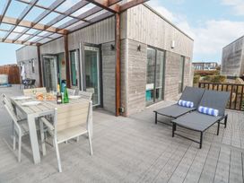 An outdoor patio area with a dining table set and two lounge chairs with towels at Hepworth in Portreath