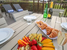An outdoor table set with plates glasses a platter of croissants and pastries a bowl of sliced fruit and bottles of sparkling water and prosecco at Hepworth in Portreath