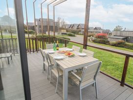 An outdoor dining area with a table set with plates drinks and food on a wooden deck at Hepworth in Portreath