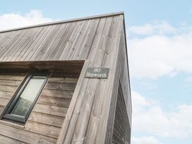 The exterior corner of a wooden building with a small window and a sign reading 80 Hepworth in Portreath