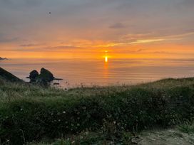 A coastal landscape with rocky formations in the ocean at sunset in Portreath