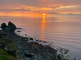 A rocky coastline with the sun setting over the ocean at Hepworth in Portreath